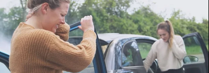 Person standing beside an open vehicle door while another person stands near a second open car door.